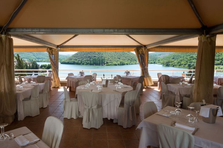Restaurant am See, umgeben von Grün und in einem schlichten Stil eingerichtet.