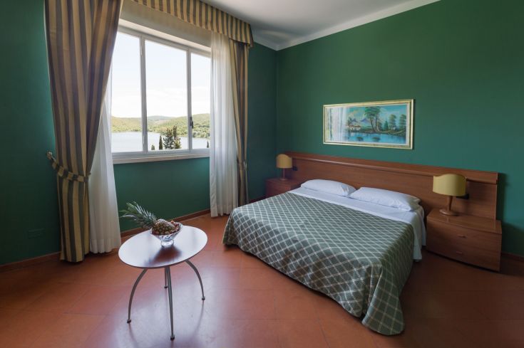 Gemütliches Zimmer mit Blick auf den See, umgeben von grünem Natur.