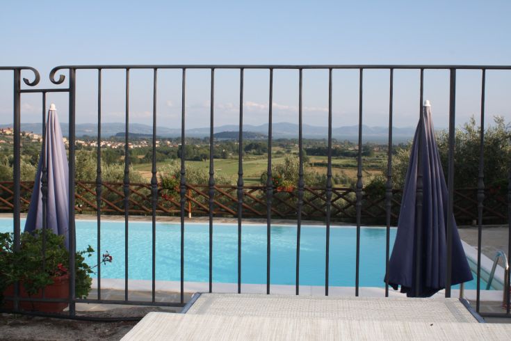 Scena tranquilla di una piscina immersa tra colline verdi e un cielo blu, perfetta per momenti di relax.