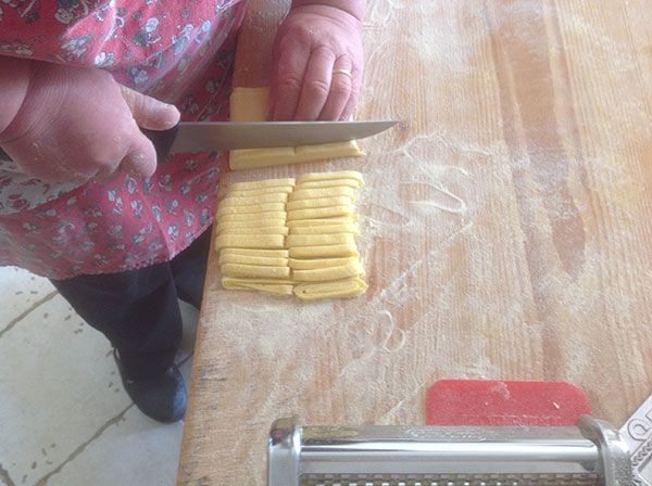 Un processo di creazione della pasta fresca, riflettendo la tradizione culinaria della regione.