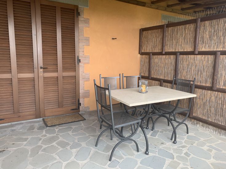 Area esterna di un agriturismo, attrezzata con tavolo e sedie, ideale per una pausa immersi nella campagna.