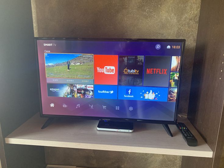 Un televisore smart presenta varie applicazioni, tra cui Netflix e YouTube, in un contesto abitativo.