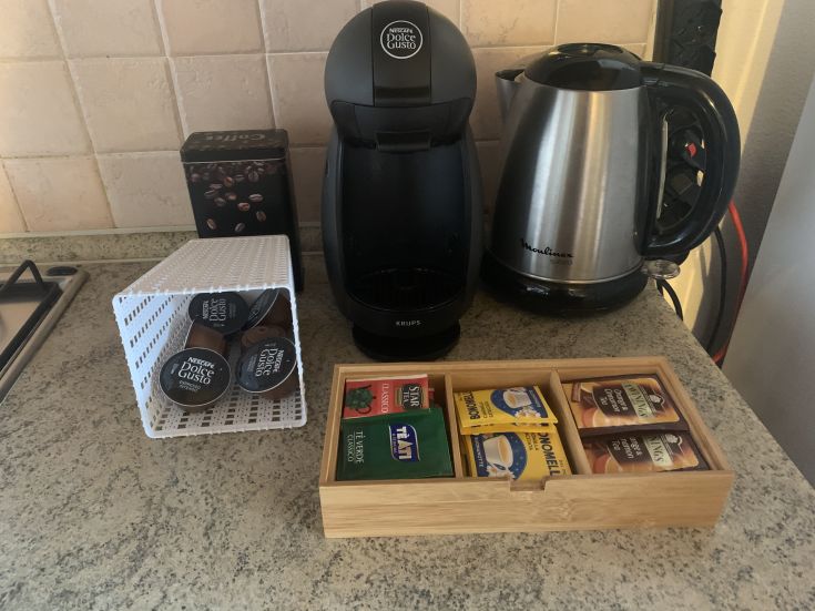 Macchina per il caffè a capsule, tazze e un kettle in una cucina funzionale.