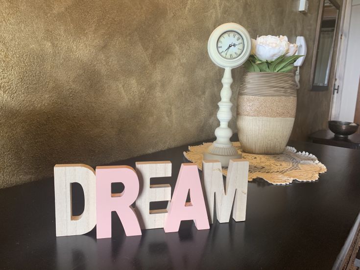 Decorazione con lettere in legno che compongono la parola 'DREAM', adatta per un ambiente interno sobrio.