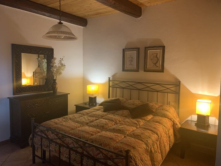 Camera da letto con letto matrimoniale, decorazioni semplici e luci calde.