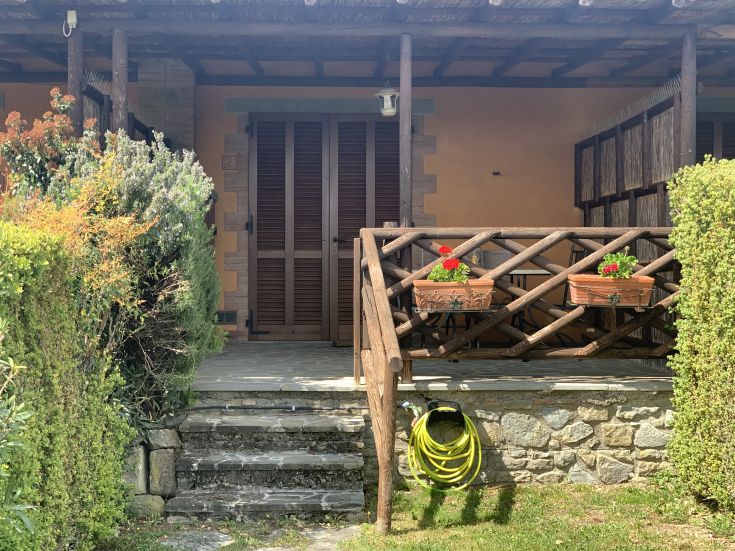 L'ingresso di un agriturismo immerso nel verde, con piante e fiori che abbelliscono lo spazio esterno.