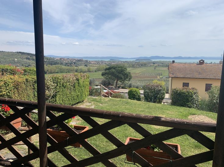 Scena tranquilla delle colline attorno al Lago Trasimeno, circondate da vegetazione lussureggiante.