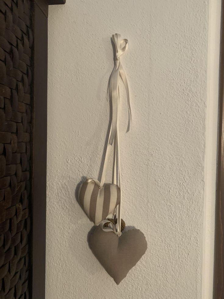 Decorazioni a forma di cuore sospese con nastro su una parete di colore chiaro.