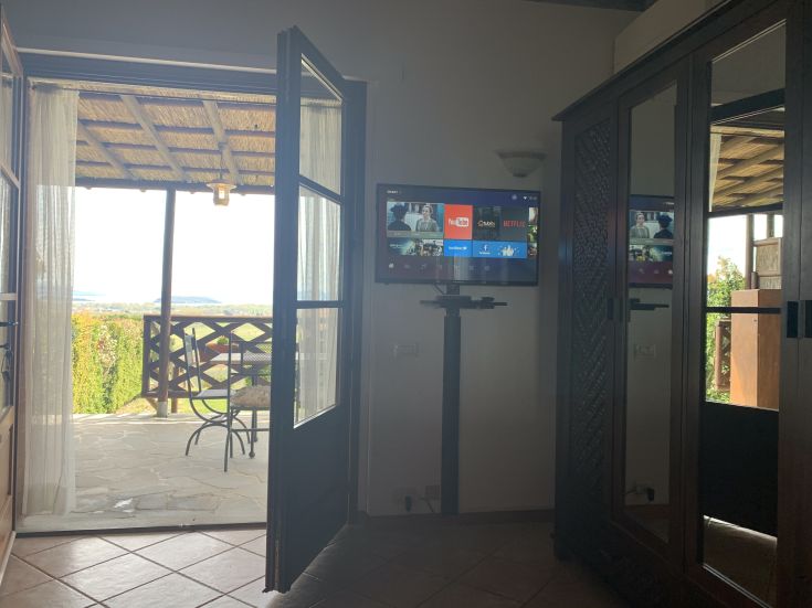 Ambiente confortevole con panorama su un paesaggio rilassante, completo di TV e arredamento semplice.