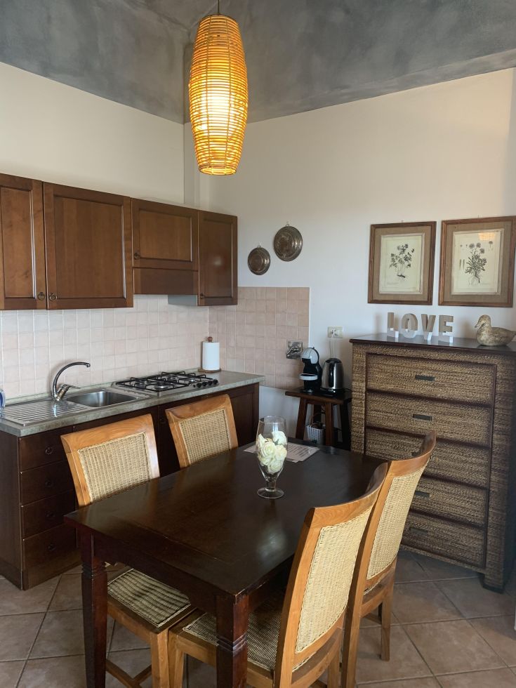 Un'accogliente cucina in stile rustico, dotata di un tavolo in legno e decorazioni semplici. Atmosfera calda e raccolta.