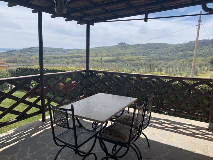 Veranda che si affaccia sulle tranquille colline del Lago Trasimeno, luogo adatto per momenti di relax.