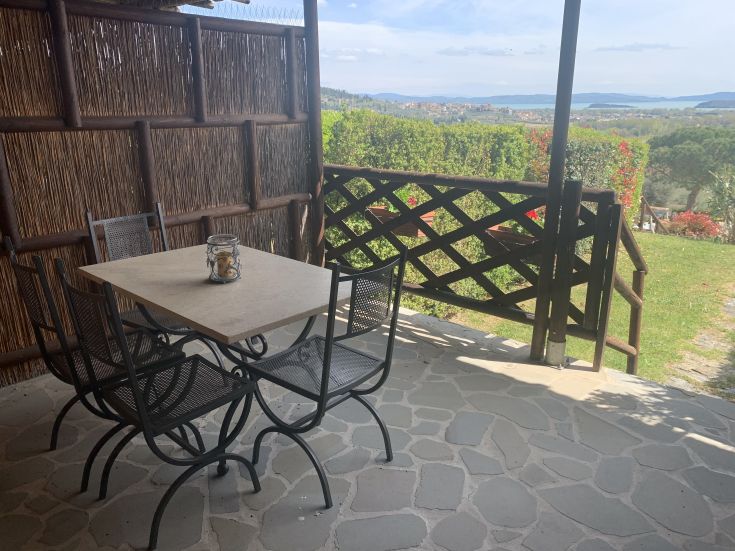 Un'area esterna tranquilla con tavolo e sedie, circondata dalla natura del Lago Trasimeno.