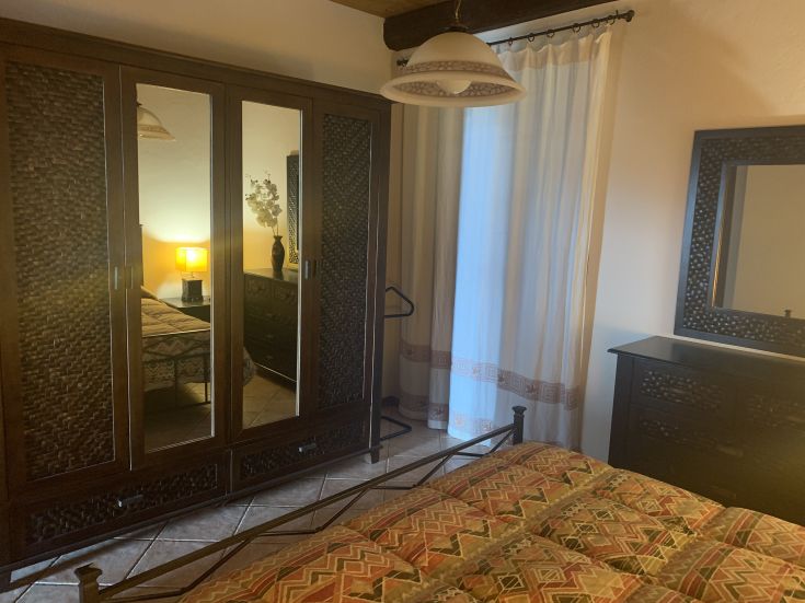 Camera semplice con armadio a specchio e letto decorato, ideale per momenti di relax.