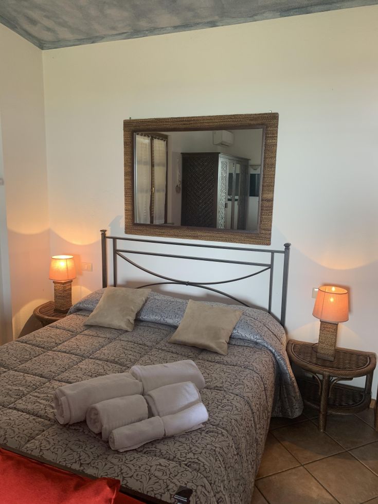 Camera spaziosa con letto matrimoniale, arredi semplici e dettagli in legno per un'atmosfera confortevole.