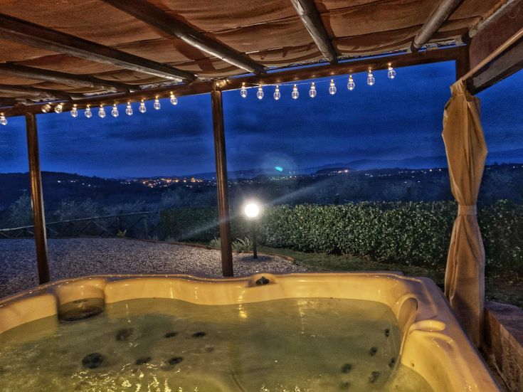 Una jacuzzi immersa in un ambiente tranquillo, circondata da colline al tramonto vicino al Lago Trasimeno.