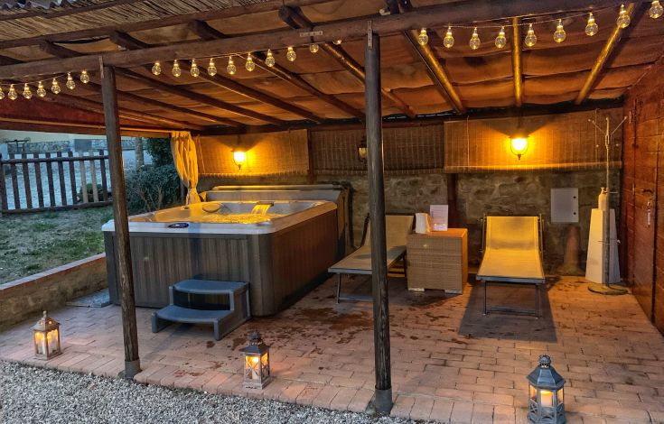 Un angolo tranquillo con vasca idromassaggio, lettini e luci soft.