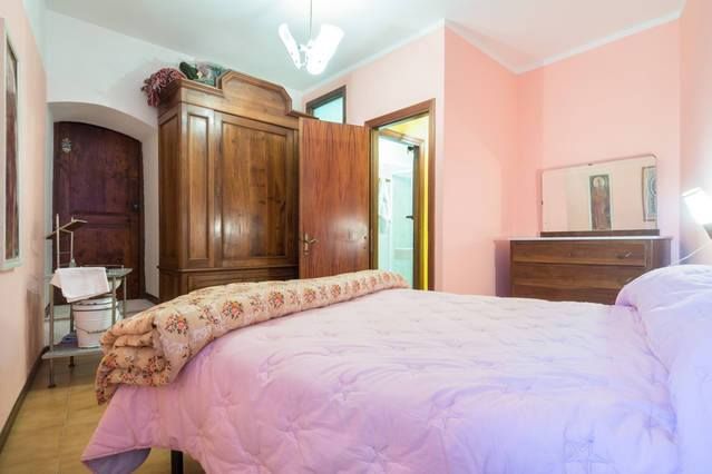 Simple space with a double bed and wooden wardrobe, warm-toned walls.