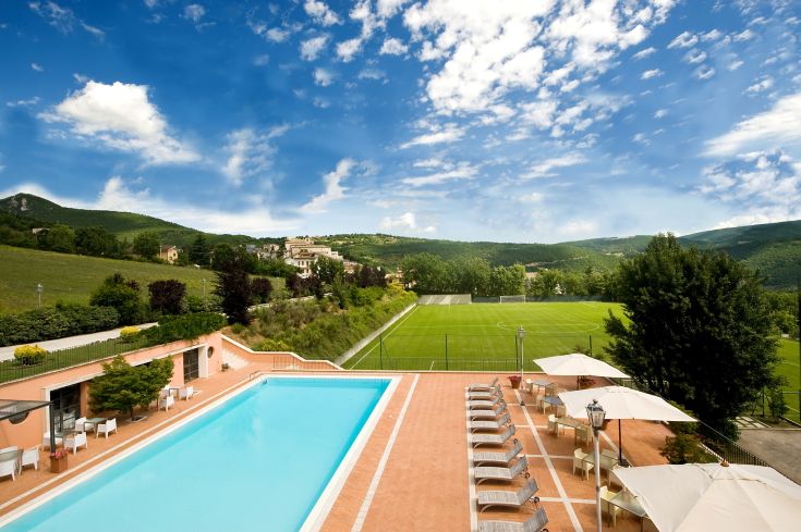 Un palazzo immerso in un vasto giardino, caratterizzato da una piscina, un campo da calcio e spazi per il relax.