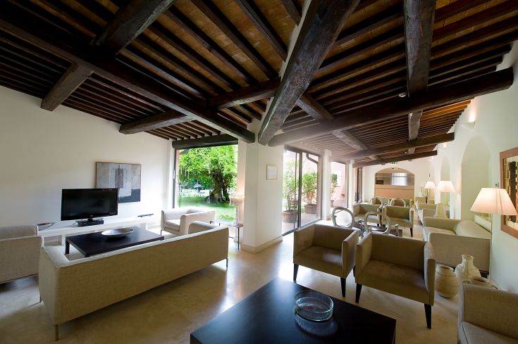 Interno di un soggiorno con arredi semplici e una piacevole vista sul verde esterno.