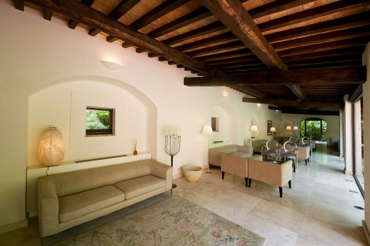 Interni caratterizzati da travi in legno a vista, ampio spazio luminoso e arredamento sobrio.