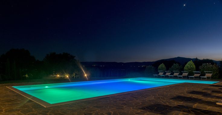 Una piscina blu illuminata in una serata tranquilla, immersa in un'atmosfera pacata.