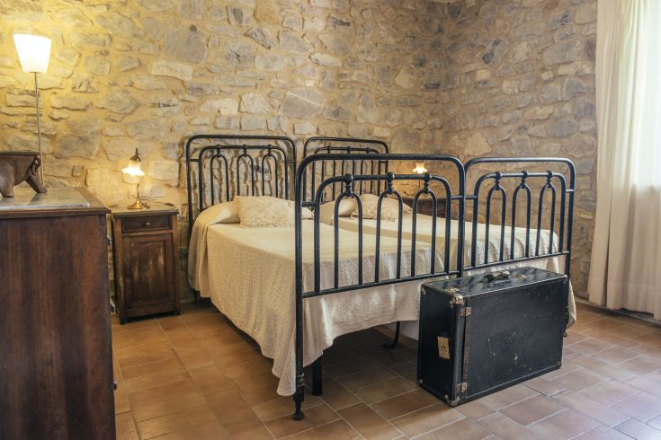 Camera semplice con letti in ferro e mobili vintage, ideale per trascorrere momenti tranquilli.