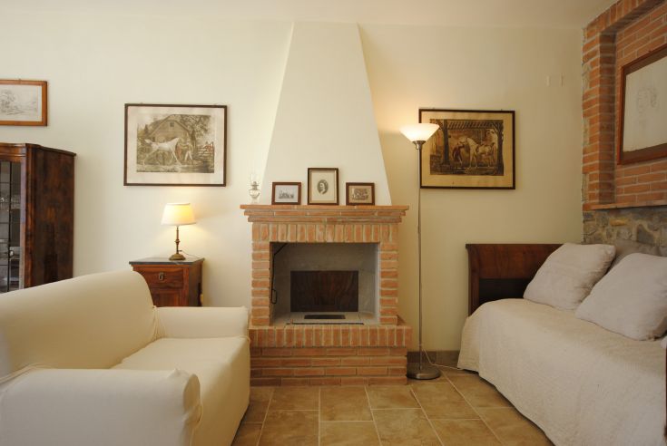 Un soggiorno caldo, dotato di un caminetto in muratura e arredato con mobili d'epoca.