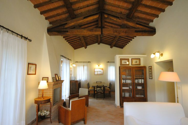 Soggiorno accogliente con soffitto in legno a travi, arredato con semplicità e comfort.