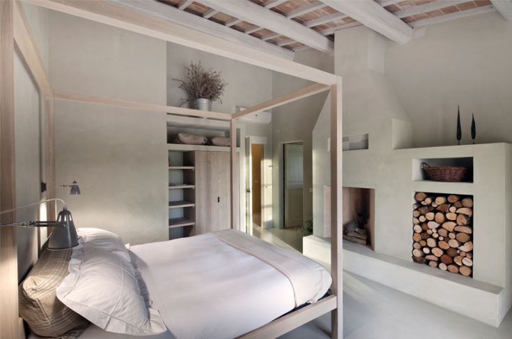 Une chambre à coucher au design simple, avec des murs clairs et une cheminée. Meublée en bois et avec des détails discrets.