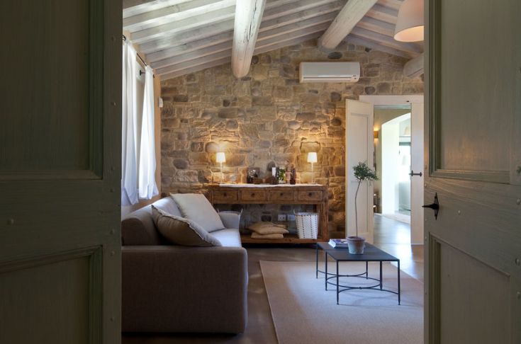 Intérieur d'un bâtiment avec des murs en pierre et un mobilier simple, un environnement sobre et confortable.