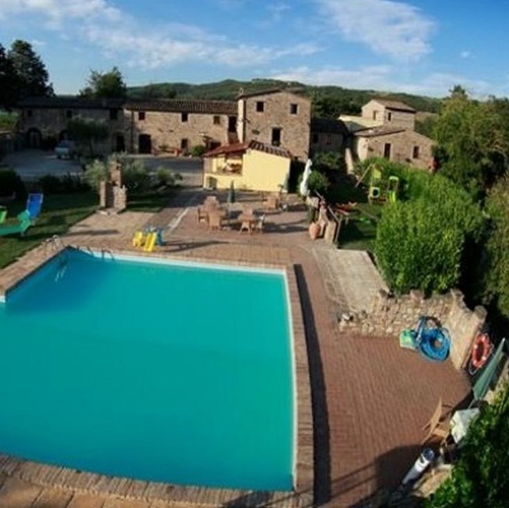 Ein ruhiger Pool, umgeben von Bäumen und Wiesen im Agriturismo Acquacalda, einem friedlichen Rückzugsort in Umbrien.