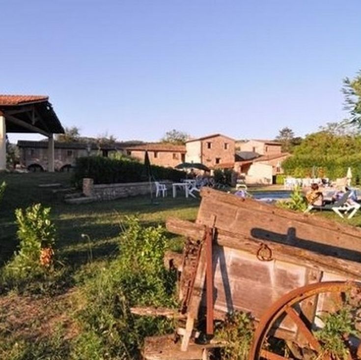 Aussicht auf einen Landgasthof, umgeben von Grün, mit einfachen Unterkünften und einem Außenpool.