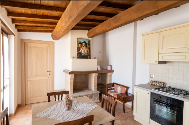 Cucina calda e accogliente con travi in legno a vista e camino, adatta per momenti di convivialità.