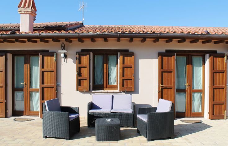 Spazio esterno di un agriturismo con arredi semplici per il relax, immerso nella natura circostante.