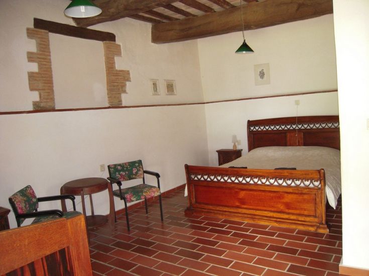 Camera ampia con mobili in legno, pavimento in terracotta e semplici dettagli decorativi.