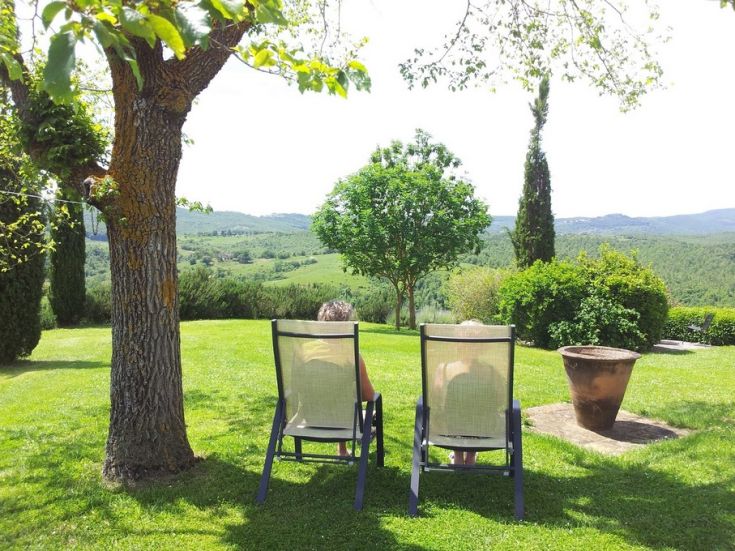 Due persone si rilassano su sdraio in un ambiente naturale circondato da un paesaggio verde.