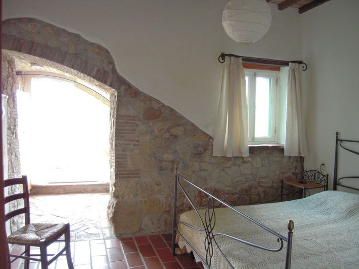 Interno di una camera confortevole con pareti in pietra e luminosità naturale.