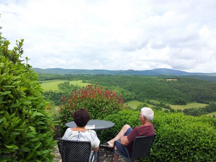 Due persone si prendono un momento di serenità osservando un panorama di verde collinare.