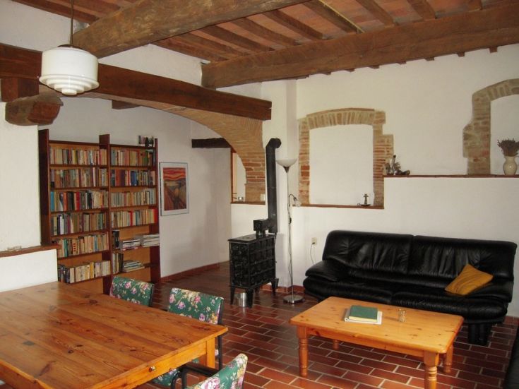 Un soggiorno semplice con travi a vista, una libreria e mobili in legno che creano un'atmosfera calda.