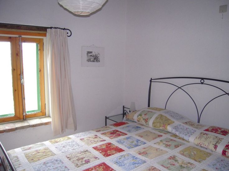 Camera semplice con letto matrimoniale e finestra che offre luce naturale.