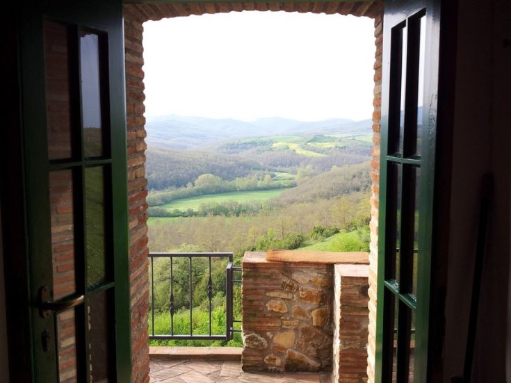Panorama dalle finestre di una casa in collina, con un paesaggio verde e collinare.