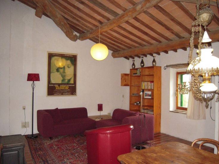 Un soggiorno semplice con poltrone rosse e un divano, illuminato da una lampada appesa al soffitto.