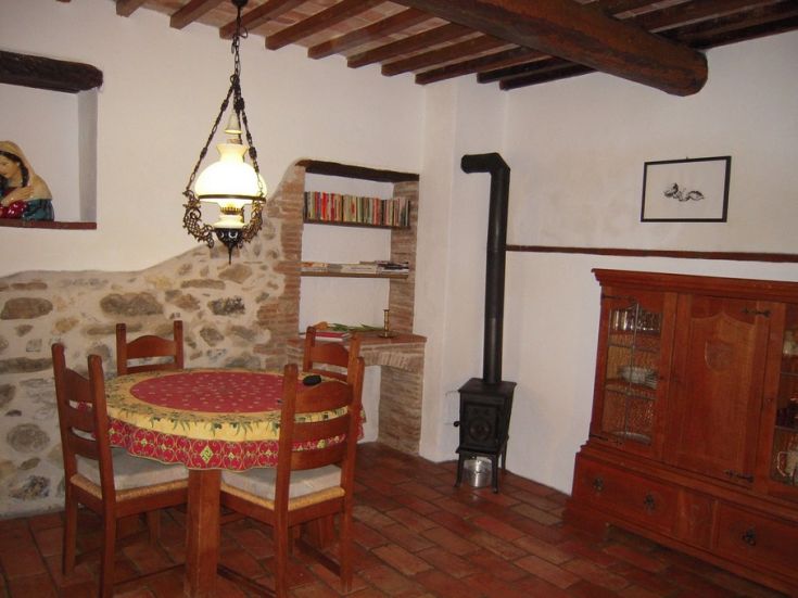 Una sala da pranzo semplice con tavolo rotondo e stufa, arredata con elementi rustici.