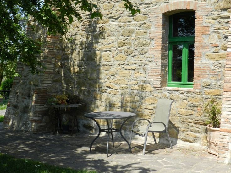 Un'area esterna accogliente con tavolo e sedie, delimitata da un muro in pietra.