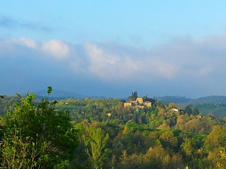 Scena umbra caratterizzata da colline verdi e un palazzo storico che si intravede all'orizzonte.