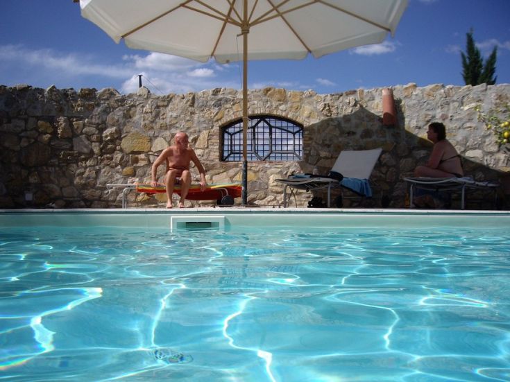 Due persone si rilassano a bordo piscina, immersi nella tranquillità del luogo circostante.