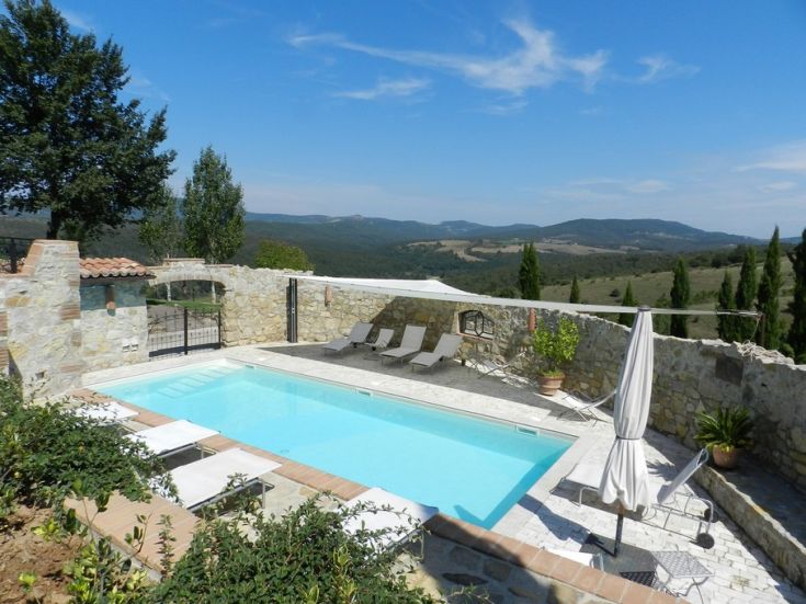 Una piscina situata in un contesto naturale, circondata da colline.