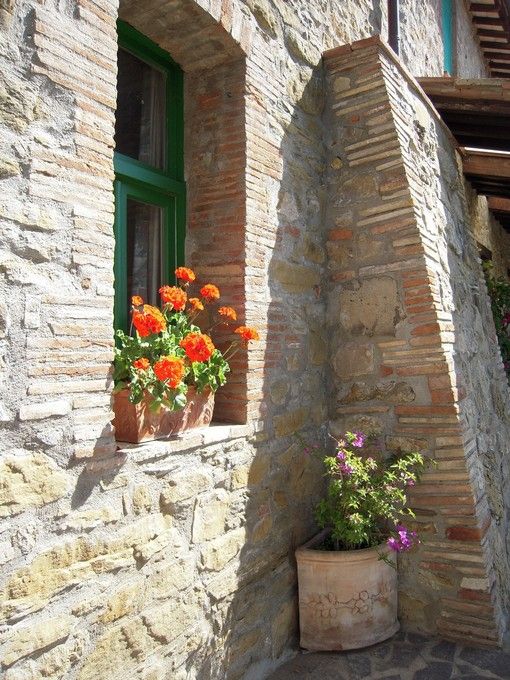 Una finestra in pietra con fiori colorati sul davanzale, tipica di molte abitazioni in Umbria.