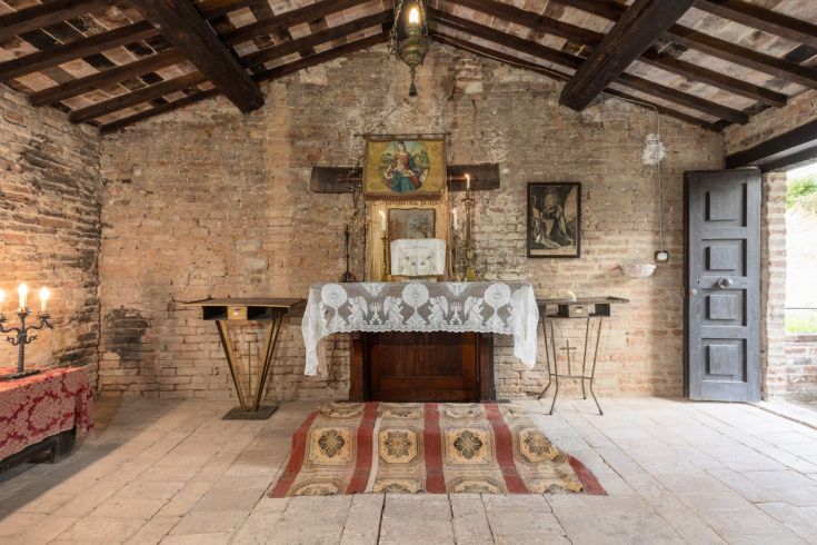 Interior of an ancient farmhouse with a decorated altar and historical architectural details.