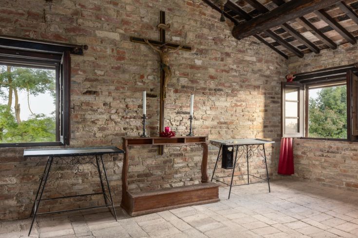 Interior of a farmhouse with stone walls and windows overlooking a natural landscape.